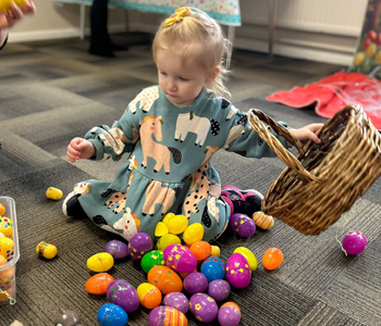 Child cleaning colourful eggs into a basket