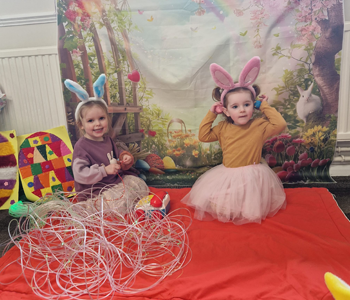 Two children wearing bunny ears playing on a mat