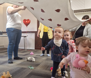 Children playing under a heart shaped blanket