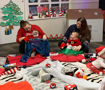 Adult male holding two children wearing christmas jumper